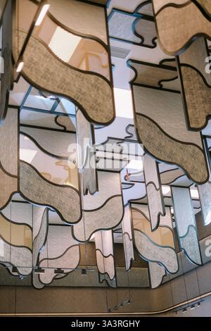 Eine einzigartige abstrakte Deckendekoration mit Stoffpaneelen mit geometrischen Formen und strukturierten Oberflächen. Die Installation schafft einen modernen Künstler Stockfoto