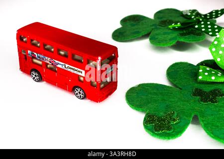 Klassischer roter Londoner Bus mit Shamrocks isoliert auf weißem Hintergrund mit Kopierraum. St. Patrick's Day Urlaub, Reisekonzept Stockfoto
