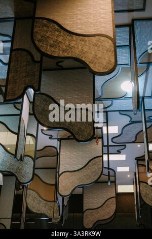 Eine optisch fesselnde Deckeninstallation mit einer Reihe organischer Formen aus strukturierten Materialien. Das Zusammenspiel von Licht und Schatten Stockfoto