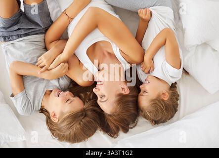 Porträt Einer glücklichen Mutter und Kinder, die zu Hause auf dem Bett liegen Stockfoto