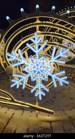 Wunderschöne glühende Weihnachten- und Neujahrsdekoration mit großen abstrakten Schneeflocken auf der Abendstraße Stockfoto