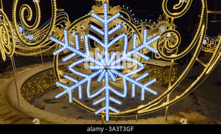 Wunderschöne glühende Weihnachten- und Neujahrsdekoration mit großen abstrakten Schneeflocken auf der Abendstraße Stockfoto