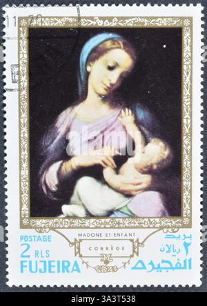 Gestempelte Briefmarke von Fujairah (Fujeira), die das Gemälde Madonna und Kind von Correggio zeigt, um 1970. Stockfoto