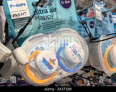 Bobruisk, Weißrussland - 2. März 2025: In einem Ladenregal werden knallbunte Schnuller mit lustigen Designs präsentiert, die perfekt für Kleinkinder geeignet sind. Stockfoto