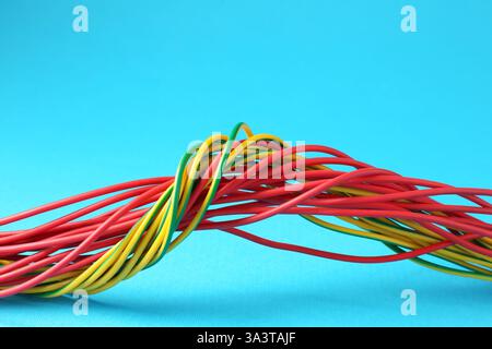 Viele farbige elektrische Drähte auf hellblauem Hintergrund, Nahaufnahme Stockfoto