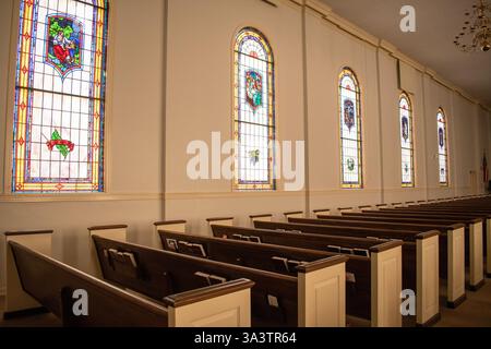 Kirchenbänke innen und Buntglasfenster Stockfoto