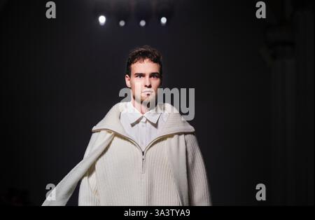 Kiew, Ukraine - 14. Februar 2025. Auf der CHUPRINA-Show läuft ein Model selbstbewusst die Landebahn hinunter und trägt einen auffälligen übergroßen weißen Mantel Stockfoto