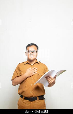 Indonesischer männlicher Angestellter in Khaki-Uniform lädt die Menschen zum Lesen von Büchern ein, der Mann wird mit einem Teil seines Körpers auf weißem Hintergrund gezeigt Stockfoto