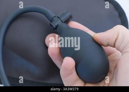 Eine Person hält eine luftaufblasbare Pumpe in der Hand, die die Form eines kleinen Ovals mit langem Griff und einer schwarzen Farbe hat. Stockfoto