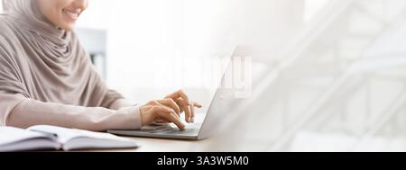 Unerkennbare muslimische Frau im Kopftuch, die im Büro am Laptop arbeitet Stockfoto