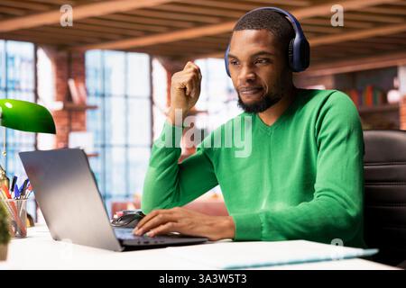 Mitarbeiter, die zu Hause Kopfhörer tragen und an der Online-Schulung auf einem Laptop teilnehmen. Telearbeiter, die zu Hause ein Audiogerät verwenden, um Schulungsvideos auf dem Notebook anzusehen Stockfoto