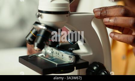afroamerikaner studiert medizinische Wissenschaft in einer Universitätsbibliothek und erforscht Viren mit einem Mikroskop. Mädchen arbeitet an der Prüfungsvorbereitung für den Erfolg einer wissenschaftlichen Karriere. Kamera B.. Stockfoto
