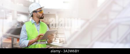 Ernsthafter nachdenklicher Millennial-Ingenieur in Schutzuniform, Brille und Schutzhelm mit Bart mit Tablette Stockfoto