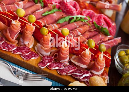 Spanische leckere Mahlzeit Schneiden von Würstchen und Schinken mit Kirschtomaten und Oliven Stockfoto