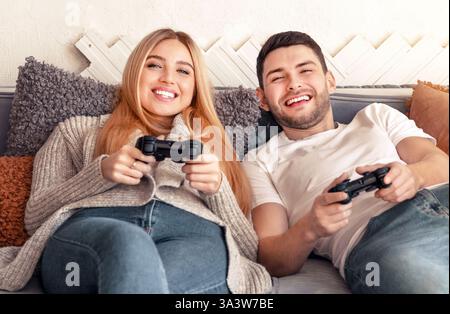 Das junge Paar spielt gerne zusammen auf einer gemütlichen Couch im Wohnzimmer Stockfoto