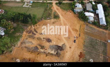 Eine hochauflösende Luftaufnahme einer Landrodung in einem ländlichen Gebiet, die Baumaschinen, unbefestigte Straßen und umliegende Grünflächen zeigt. Ideal für Stockfoto