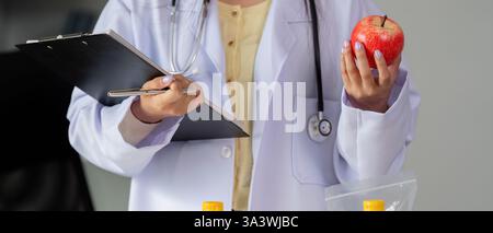Ernährungsberatung und Diätetik-Wellness. Ein medizinischer Fachmann hält einen frischen Apfel und betont dabei die gesunde Ernährung. Stockfoto