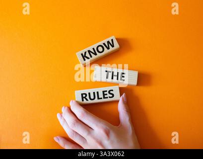 Kennen Sie das Regelsymbol. Holzblöcke mit Worten kennen die Regeln. Wunderschöner orangefarbener Hintergrund. Geschäftsmann Hand. Und kennen Sie das Regelkonzept. Co Stockfoto