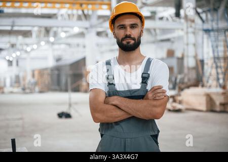 Porträt mit überkreuzten Armen. Industriearbeiter im Holzlager. Stockfoto
