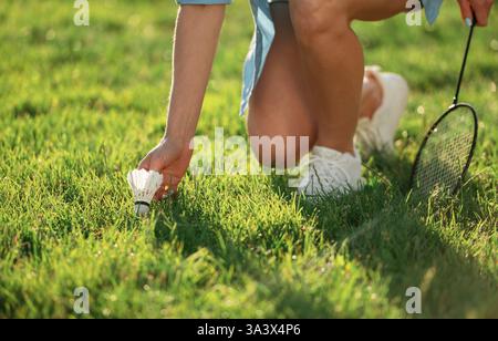 Nahaufnahme einer Frau, die Shuttlecock vom Boden nimmt. Stockfoto