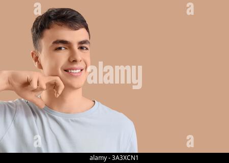 Junger Mann, der Gesichtsaufbauübung auf beigefarbenem Hintergrund macht Stockfoto