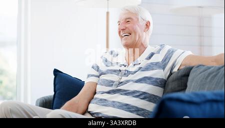 Senior Mann, lachend und reflektierend auf dem Sofa, glücklich und Erinnerung mit lustigem Geheimnis in der Lounge für den Ruhestand. Ältere Person, lächeln und erinnern Sie sich an die Geschichte Stockfoto