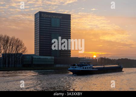 Rijkswaterstaat Gebäude. Hauptsitz der Generaldirektion öffentliche Arbeiten und Wasserwirtschaft, Sonnenaufgang mit Boot auf dem Kanal. Stockfoto