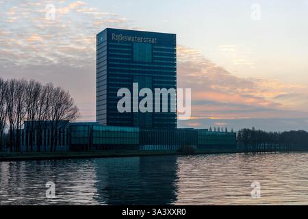 Rijkswaterstaat Gebäude. Hauptsitz der Generaldirektion öffentliche Arbeiten und Wasserwirtschaft, Sonnenaufgang mit Boot auf dem Kanal. Stockfoto