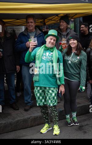 Verheiratet und grün gekleidet, heben ihr Bier auf, während sie 2025 die St. Patrick's Day Parade vor Slainte of Peekskill in New Yor sehen Stockfoto