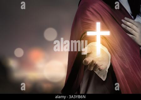 Jesus Christus streckt mit offenen Armen aus und zeigt ein hell erleuchtetes Kreuz. Das Konzept von Christentum, Glauben und Spiritualität Stockfoto