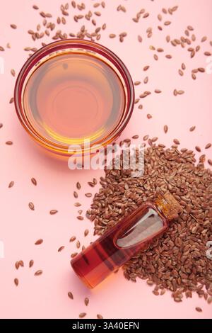 Leinsamen mit Leinsamenöl in der Schüssel auf rosa Hintergrund. Vertikales Foto. Draufsicht Stockfoto