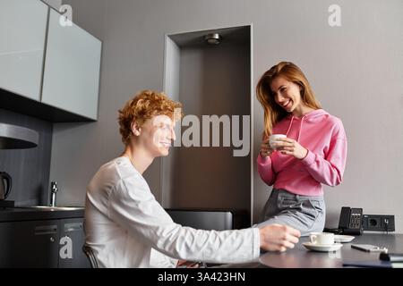 Ein junges Paar teilt sich mit Lachen und Wärme, während es sich in einem gemütlichen Hotelzimmer umschließt. Stockfoto