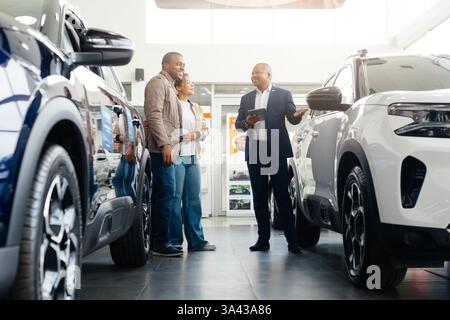 Afroamerikanisches Paar diskutiert Autokauf mit Händler im Autohändler Stockfoto