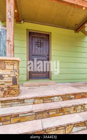 Ein wunderschönes Gewächshaus mit einer charmanten Holztür und gut gearbeiteten Steintreppen, die anmutig hinauf führen Stockfoto