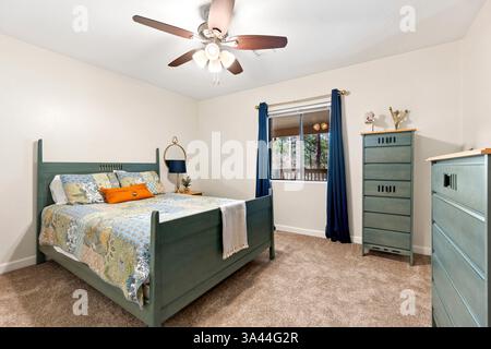 Ein gemütliches Schlafzimmer mit wichtigen Möbeln, darunter ein bequemes Bett, eine stilvolle Kommode und ein kühlender Deckenventilator zur Verbesserung der Luftzirkulation Stockfoto