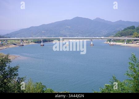 Gwangyang, Südkorea - 3. Oktober 2021: Eine moderne Brücke überspannt den Seomjin River und verbindet die Landschaft vor einem Hintergrund sanfter Berge. Stockfoto