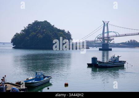 Gwangyang, Südkorea - 3. Oktober 2021: Malerischer Blick auf die Byeol Heneun Bridge, die Baealdo mit dem Festland verbindet, mit Fischerbooten Stockfoto