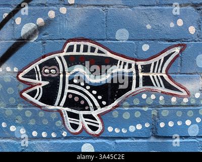 Stilisierter Fisch auf einer blauen Ziegelwand mit Mustern und Designs, die von Volkskunst inspiriert sind. Stockfoto