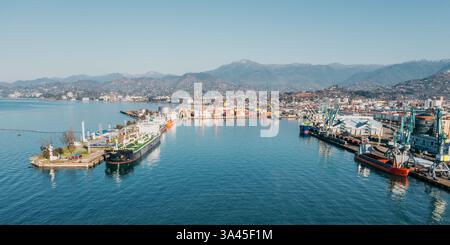 Seehafen mit Frachtschiffen, Öltankern und Industriekränen gegen Berge. Handelshafen für internationalen Handel, Versand und Containerlogistik. Import- und Exportindustrie. Stockfoto