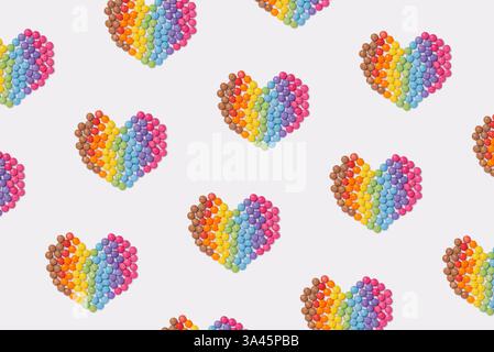 Bunte Süßigkeiten bilden eine Herzform auf weißem Hintergrund. Regenbogenfarbene Süßigkeiten. Glücklichkeits- und Fröhlichkeits-Konzept, Blick von oben Stockfoto