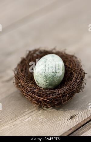 Osterei in einem kleinen Nest auf Holzboden Stockfoto