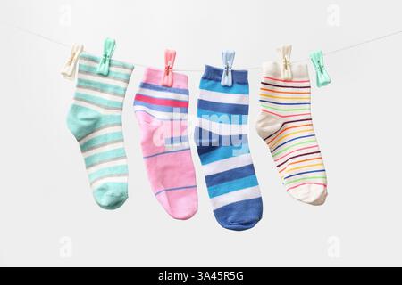 Verschiedene Socken, die vor hellem Hintergrund am Seil hängen Stockfoto