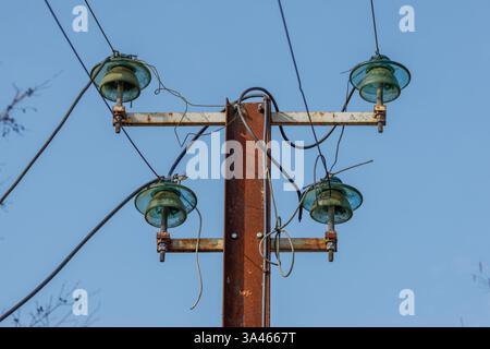 Rostiger Elektromast mit Glasisolierungen. Rostiger Elektromast mit Glasisolatoren gegen klaren blauen Himmel. Stockfoto