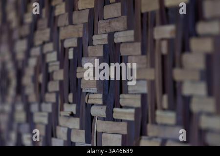 Eine Nahaufnahme der asiatischen gewebten Bambusstruktur mit einer Mischung aus hellen und dunklen Streifen, die ein geometrisches Muster erzeugt. Stockfoto