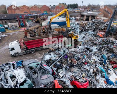 Ein Stapel beschädigter Fahrzeuge und Schrott im Hof eines Schrotthändlers, der zum Recycling auf einen LKW geladen und Zölle auf Export und Import erhoben wird Stockfoto