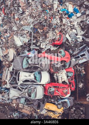 Luftaufnahme direkt über einem Stapel beschädigter Fahrzeuge und Metallschrott auf dem Hof eines Schrotthändlers zum Recycling und zur Einführung von Zöllen für Export und Import Stockfoto