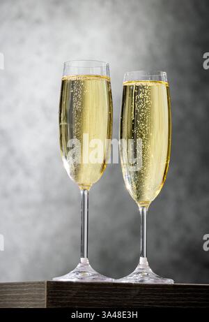 Zwei Gläser goldener Sekt auf grauem Restauranttisch und Wandhintergrund Stockfoto