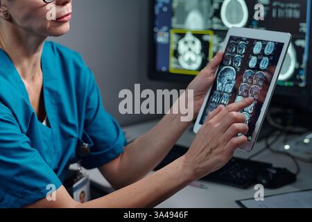 Medizinischer Facharzt bei der Analyse von Hirnscans auf Tablettengeräten in modernen medizinischen Einrichtungen. Überprüfung von Patientendaten und Interpretation von MRT-Ergebnissen für Diagnosezustände Stockfoto