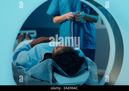 Ein Patient, der auf dem Untersuchungstisch liegt, mit medizinischem Personal und Ausrüstung um ihn herum, wodurch der Schwerpunkt auf die medizinische Umgebung gelegt wird und die Patientenversorgung betont wird Stockfoto