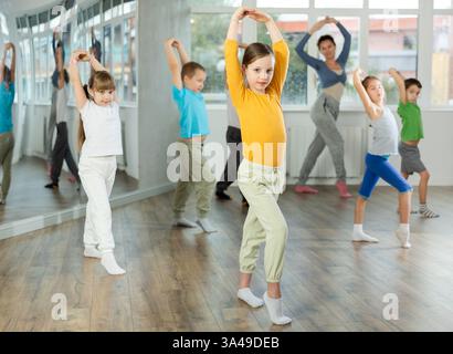 Kinder, die modernen Tanz trainieren, bewegen sich gemeinsam im Studio unter der Leitung des Lehrers Stockfoto